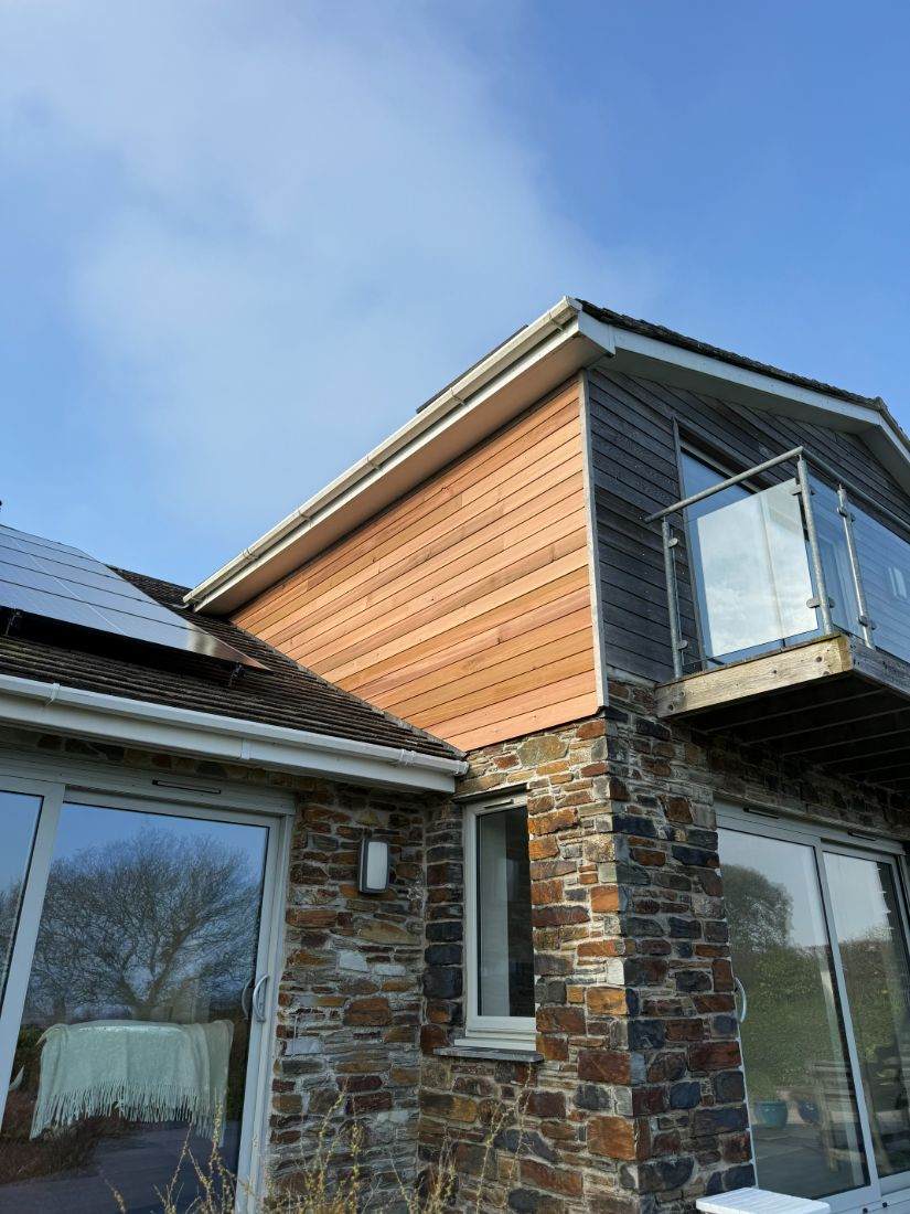 A contemporary Cornish home with a natural slate roof and a new white fascia, soffit and gutter line