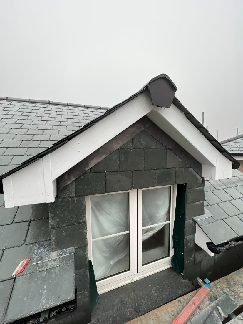 A dormer finished in vertical hung slate with crisp white bargeboards