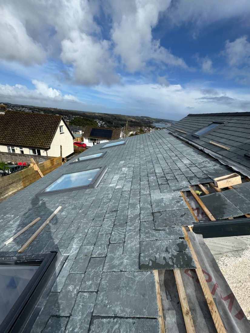 A slate roof extension with Velux roof windows overlooking Cornish rooftops and the estuary