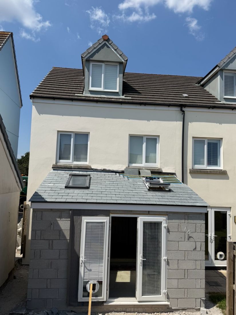 A completed house with a slate-clad dormer above and roof windows set into the lower pitched roof