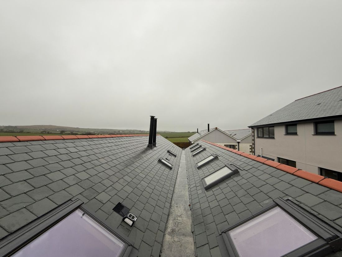 A barn conversion re-roofed edge to edge in Brazilian slate, with a run of Velux roof windows down both pitches and a lead-lined valley between them