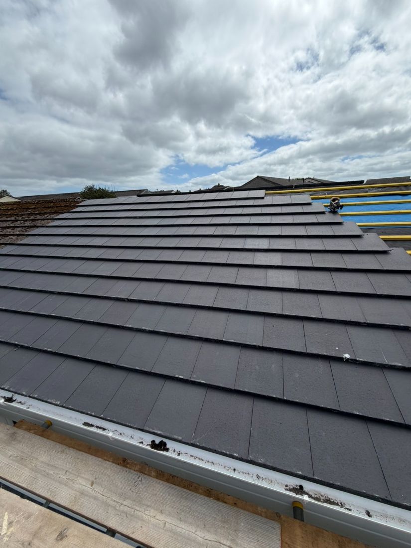 A completed pitched roof covered in new dark grey tiles