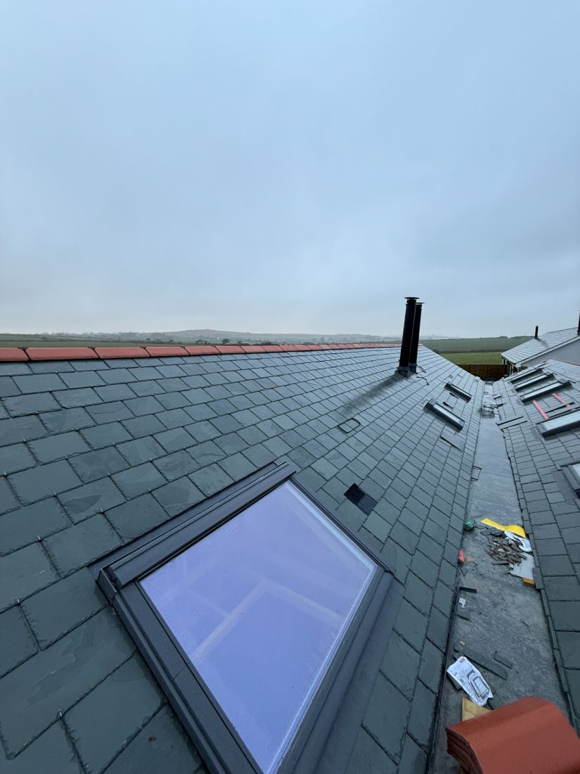 A Velux roof window set flush into new natural slate with neat flashing