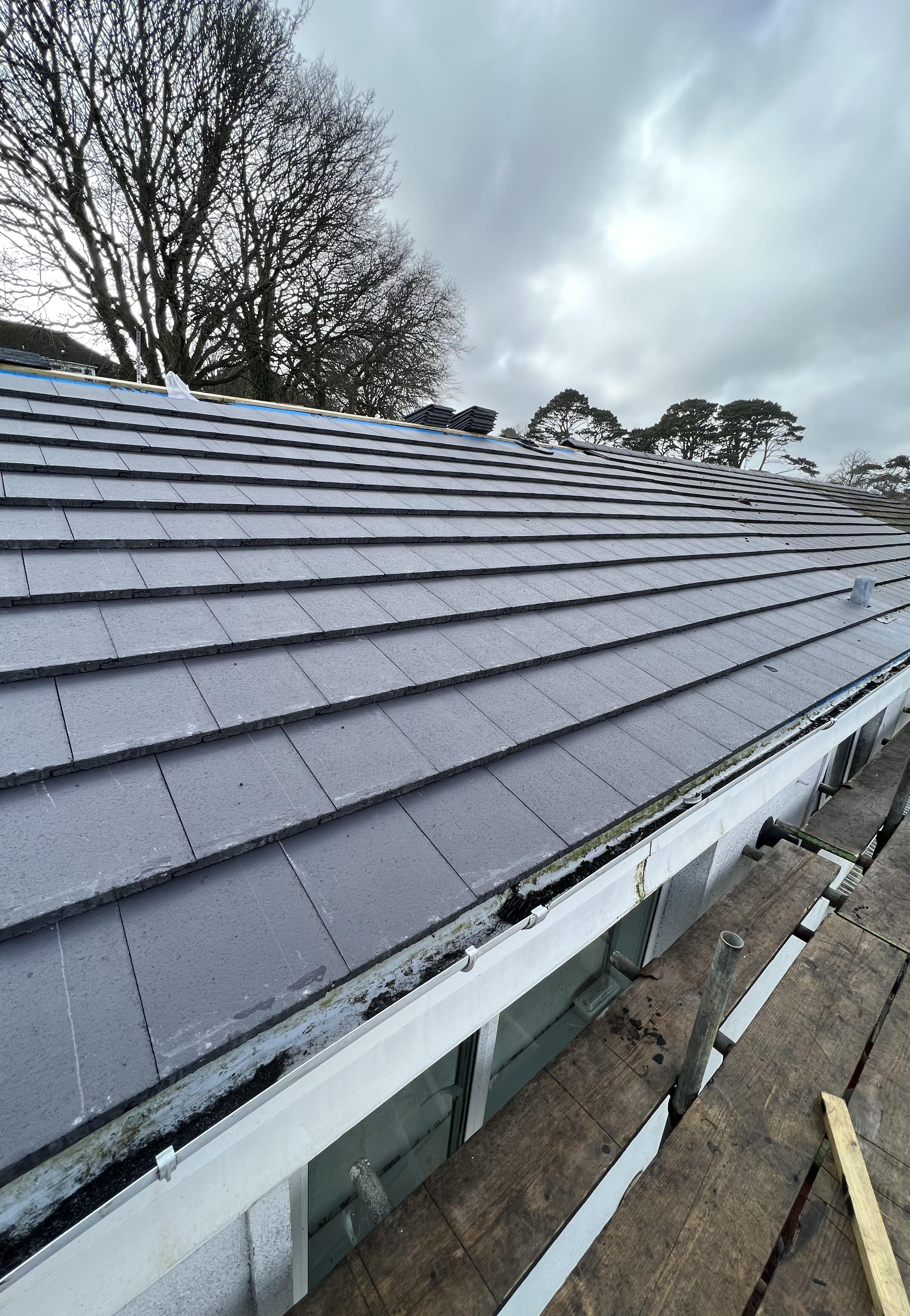 A new grey tile roof neatly joined into the neighbour's existing roof